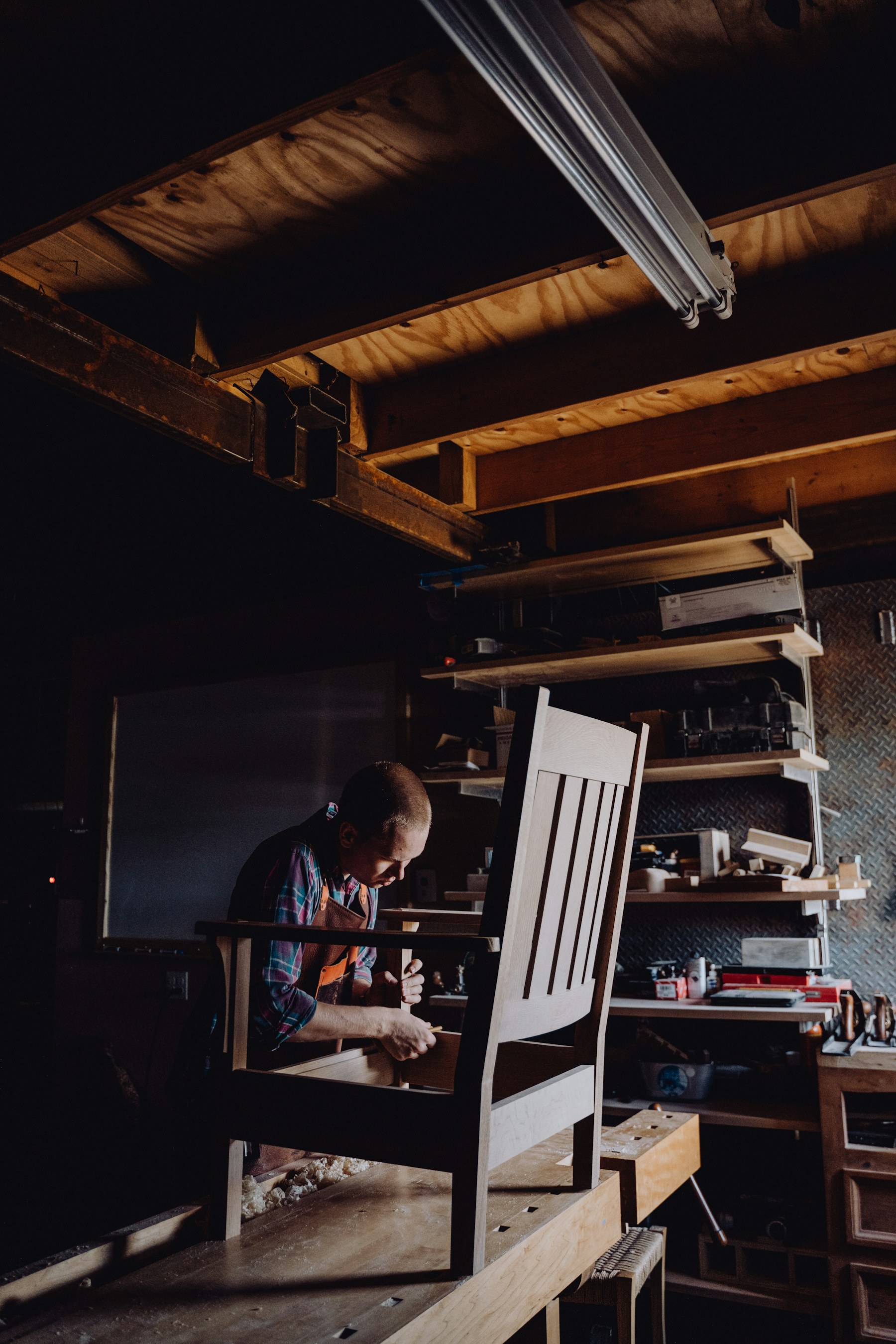 Craftsperson working on a chair in a woodworking workshop